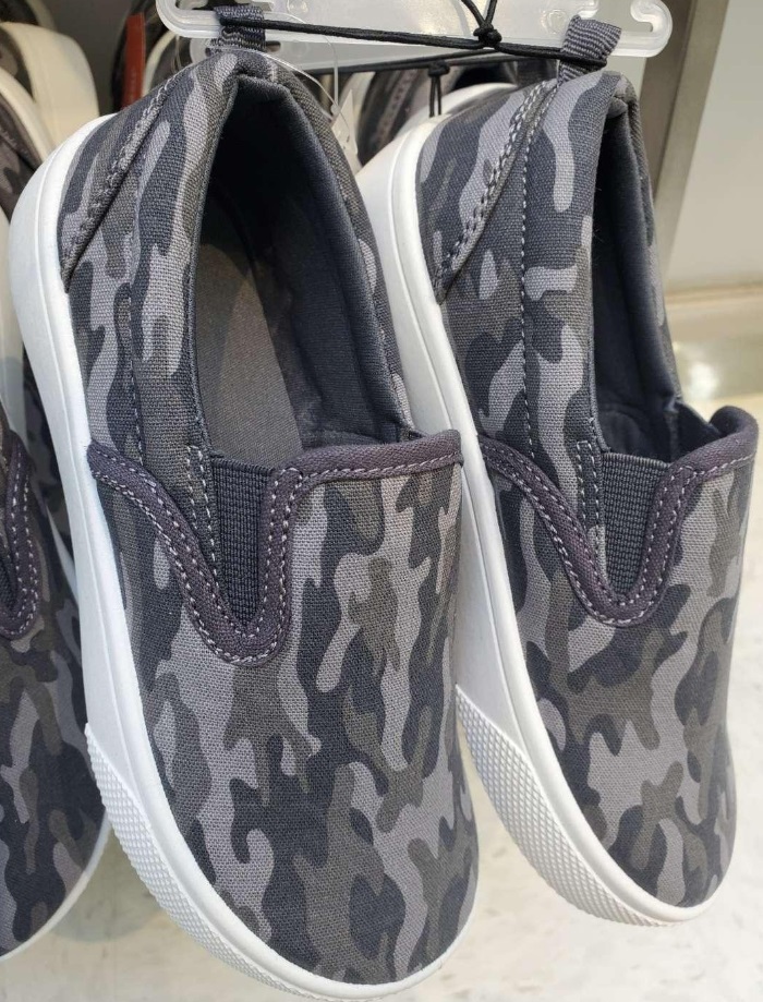 A pair of grey vertical patterned camo shoes, hanging up at a store.